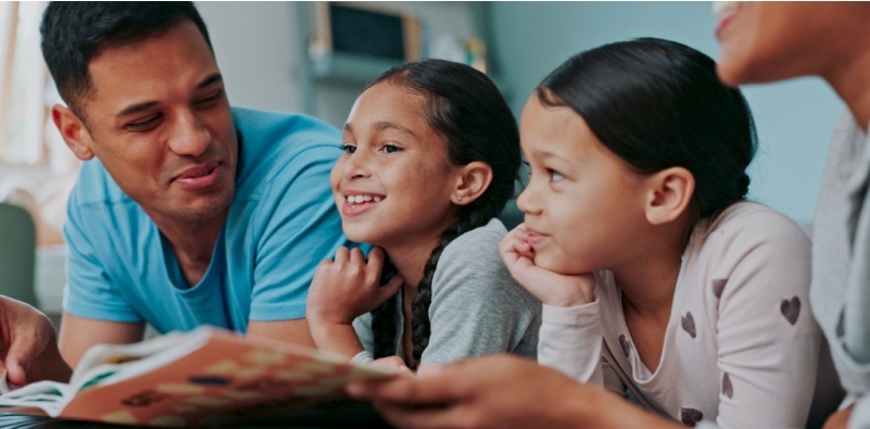 Family taking a break from the screens by reading a book together